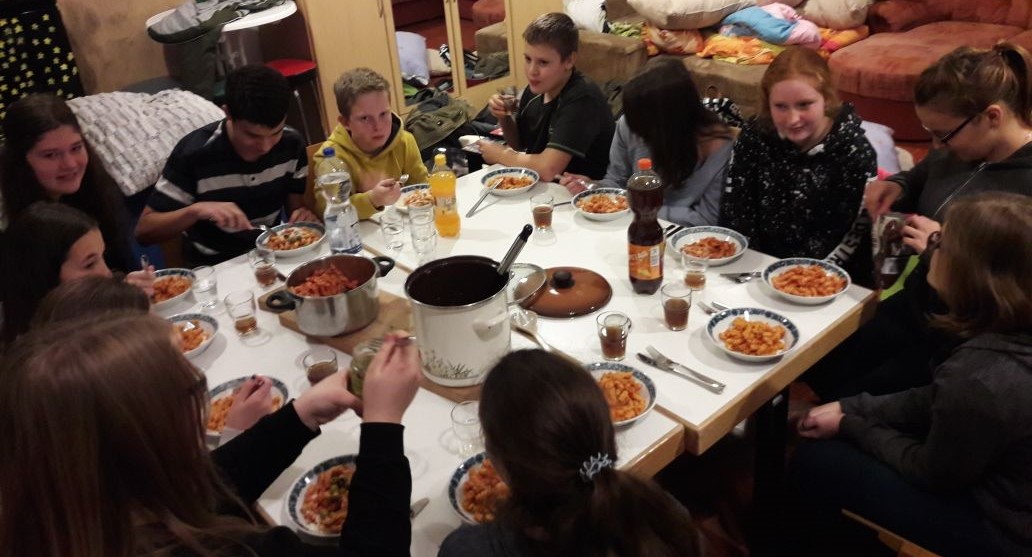 Jugendliche sitzen um Tisch mit Essen